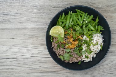 Dry noodles with pure chicken (high protein), brown rice vermicelli, served with boiled long beans and fresh lemon on wooden table. Top view.