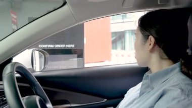 Asyalı genç bir kadın yiyecek ve içecekler için sipariş verir ya da ödeme yapar ve kredi kartıyla ya arabayla ya da arabayla geçer. Temassız ödeme, Temassız Teslimat.