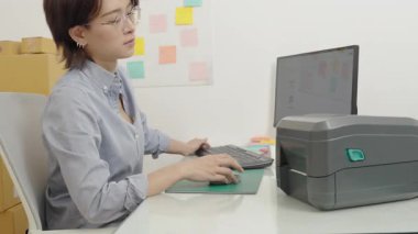 Asyalı kadın inşaat işçisi ofise not yazıyor ya da yapıştırıyor.