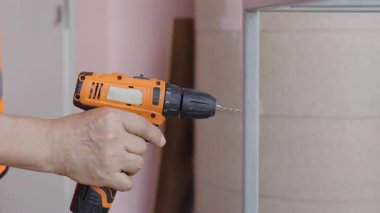 Yansıtıcı yelek giyen erkek işçiler çelik ya da alüminyum delmek için kablosuz çelik matkaplar kullanırlar..