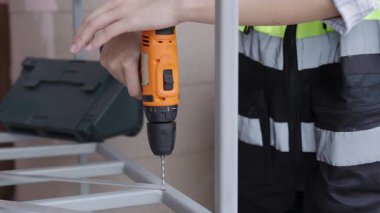 Yansıtıcı yelek giyen kadın işçiler çelik ya da alüminyum delmek için kablosuz çelik matkaplar kullanıyorlar..