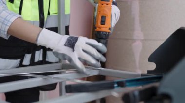 Yansıtıcı yelek giyen kadın işçiler çelik ya da alüminyum delmek için kablosuz çelik matkaplar kullanıyorlar..