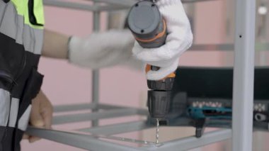 Yansıtıcı yelek giyen kadın işçiler çelik ya da alüminyum delmek için kablosuz çelik matkaplar kullanıyorlar..