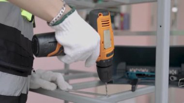 Yansıtıcı yelek giyen kadın işçiler çelik ya da alüminyum delmek için kablosuz çelik matkaplar kullanıyorlar..