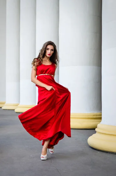 Девушка в красном платье возле колонн — стоковое фото