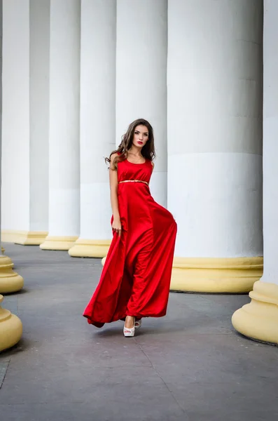 Ragazza in abito rosso vicino colonne — Foto Stock