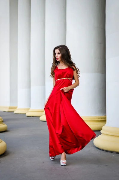Menina em vestido vermelho perto de colunas — Fotografia de Stock