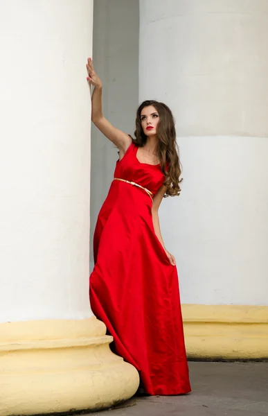 Menina em vestido vermelho perto de colunas — Fotografia de Stock