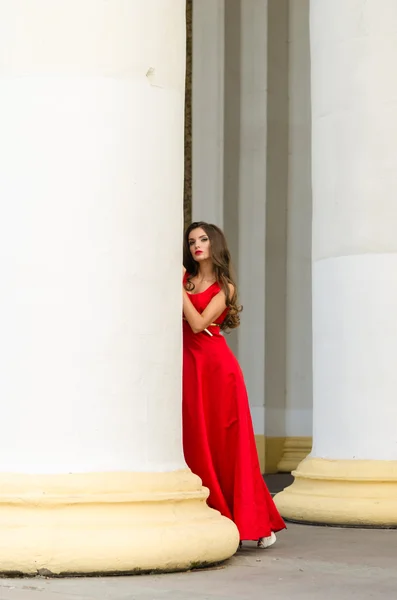 Menina em vestido vermelho perto de colunas — Fotografia de Stock