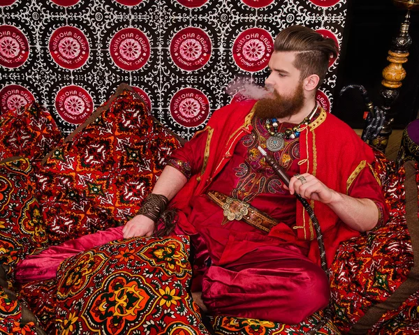 Man in oriental costume smoking hookah Stock Photo