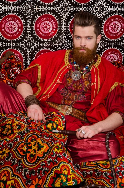 Man in oriental costume smoking hookah Stock Image