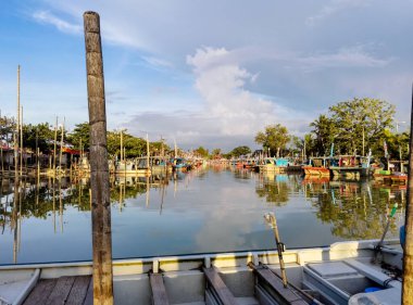 Eski iskele balıkçı köyüne park etmiş renkli ahşap balıkçı tekneleri, balıkçı tekneleri, mangrov ormanları ve su üzerinde mavi gökyüzü, Parit Jawa, Malezya