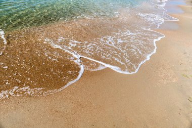 Kumsalda deniz köpüğüyle dalgalar