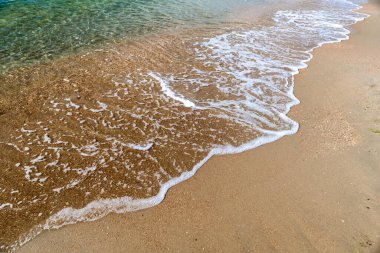 Kumsalda deniz köpüğüyle dalgalar
