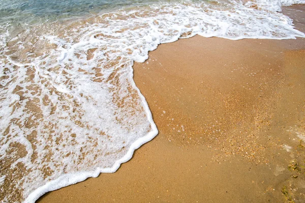 Waves with sea foam on a sandy beach