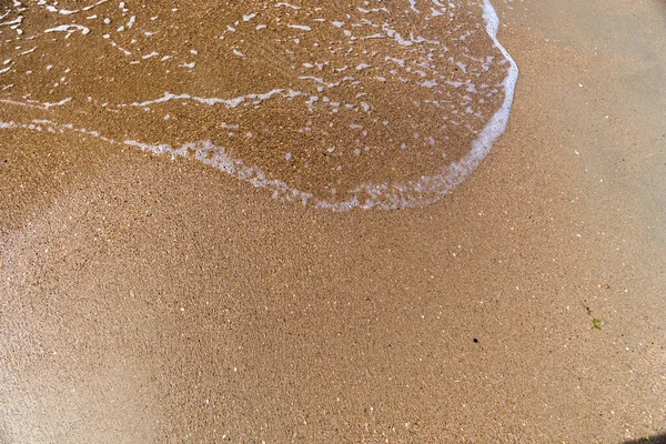 Waves with sea foam on a sandy beach — Stock Photo, Image