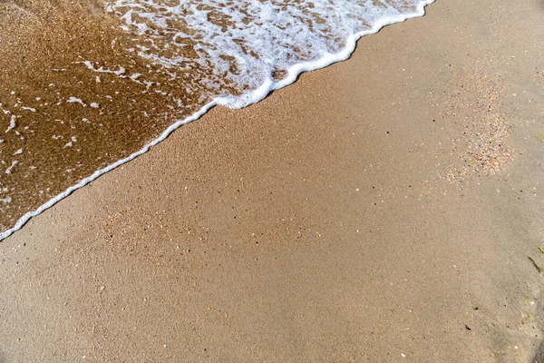 Wellen mit Meeresschaum an einem Sandstrand lizenzfreie Stockfotos