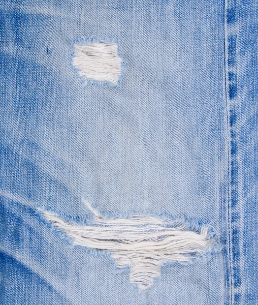 Blue jean texture with a hole and threads showing — Stock Photo, Image