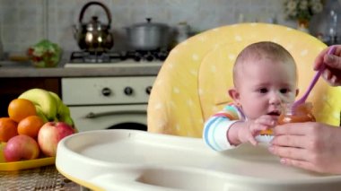 Küçük anne bebek püre meyveli sebzelerle besleniyor. seçici odak