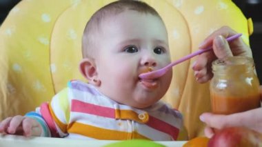 Küçük anne bebek püre meyveli sebzelerle besleniyor. seçici odak