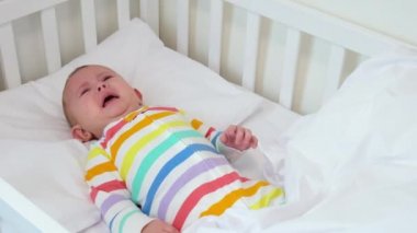 Anne ağlayan bebeği yatağından kaldırır. Seçici odak.