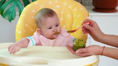 Küçük anne bebek püre meyveli sebzelerle besleniyor. seçici odak