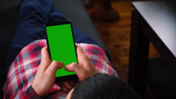 Man met een telefoon in zijn handen, groen scherm. Selectieve focus. — Stockvideo