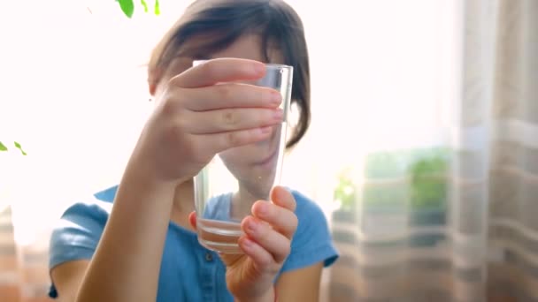 Το παιδί κοιτάζει το νερό σε ένα ποτήρι. Επιλεκτική εστίαση. — Αρχείο Βίντεο
