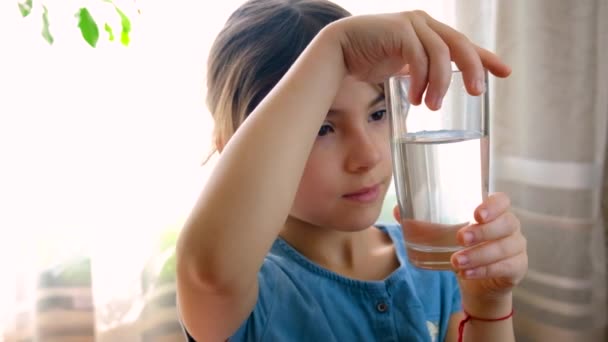 Dítě se dívá na vodu ve sklenici. Selektivní zaměření. — Stock video