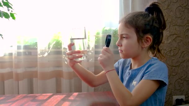 子供は虫眼鏡で水を見る。選択的焦点. — ストック動画