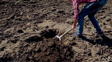 Bir adam bahçede bir çukur kazıyor. Seçici odak.