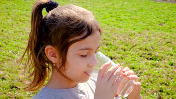 The child drinks water from a glass. Selective focus. — Stock Video