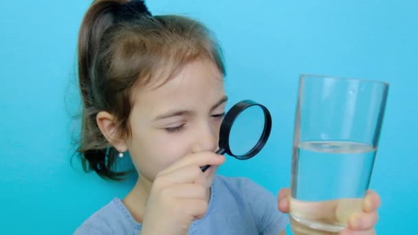 Barnet tittar på vattnet med ett förstoringsglas. Selektiv inriktning. — Stockvideo