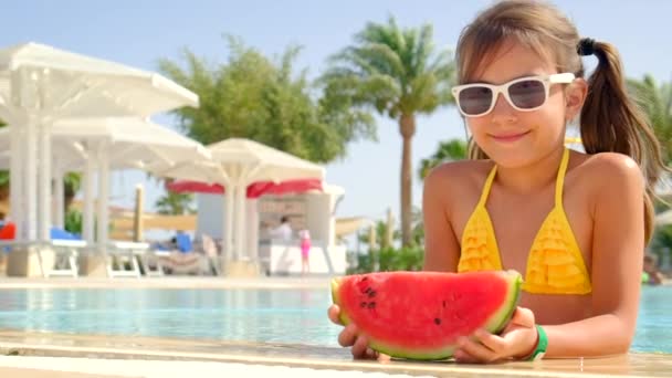 L'enfant mange une pastèque près de la piscine. Concentration sélective. — Video