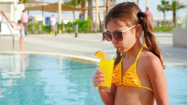 L'enfant boit un cocktail dans la piscine. Concentration sélective. — Video