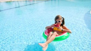 Çocuk havuzun yanında bir karpuz yiyor. Seçici odak.