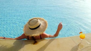 Havuz kenarında kokteyl içen bir kadın. Seçici odak.