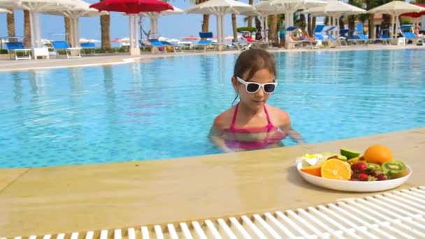 어린 소녀는 수영장에서 과일을 먹습니다. 선택적 초점. — 비디오