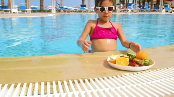 어린 소녀는 수영장에서 과일을 먹습니다. 선택적 초점. — 비디오