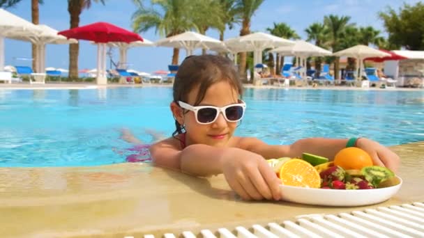 Дитяча дівчинка їсть фрукти в басейні. Вибірковий фокус . — стокове відео