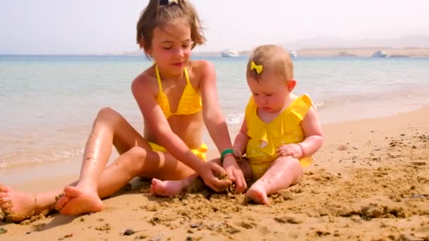 Les enfants jouent avec le sable sur la plage. Concentration sélective. — Video