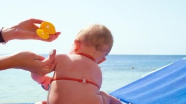 Bebek Maj plajda güneş kremi sürüyor. seçici odak.