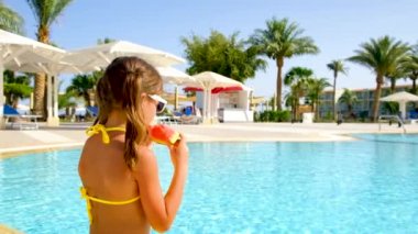 Çocuk havuzun yanında karpuz yiyor. seçici odak.