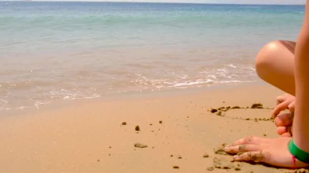 Barnet ritar på sanden på stranden. selektivt fokus. — Stockvideo