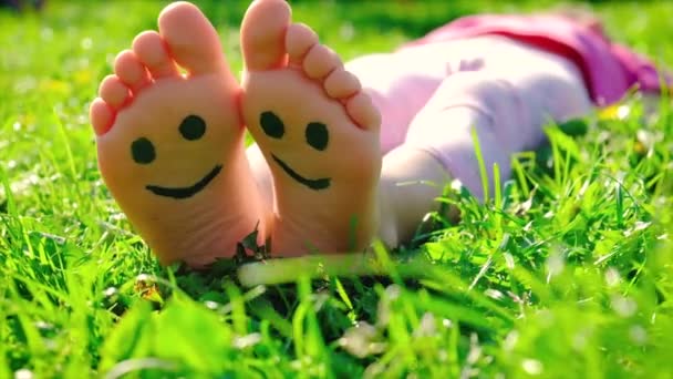 Dziecięce nóżki na trawie, letni uśmiech. Skupienie selektywne. — Wideo stockowe