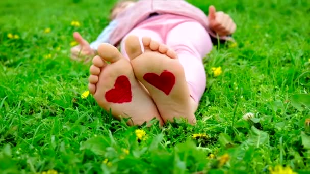 Een kind op haar voeten is een getekend hart. Selectieve focus. — Stockvideo