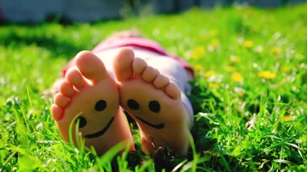 Niños pies en la hierba verano dibujado sonrisa. Enfoque selectivo. — Vídeo de stock