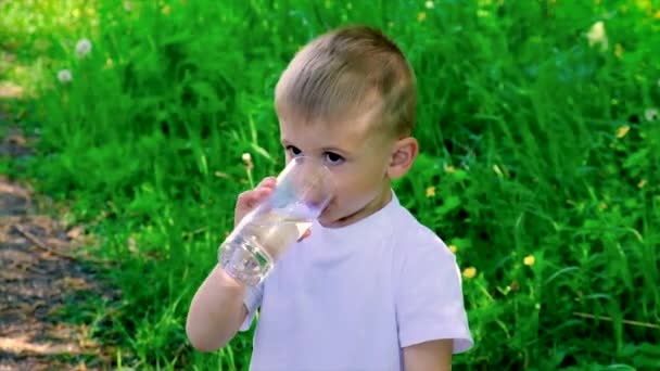L'enfant boit de l'eau dans un verre. Concentration sélective. — Video