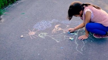 Çocuk asfalta bir aile çiziyor. Seçici odak.