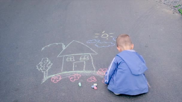 The child draws a house on the asphalt. Selective focus. — Stock Video